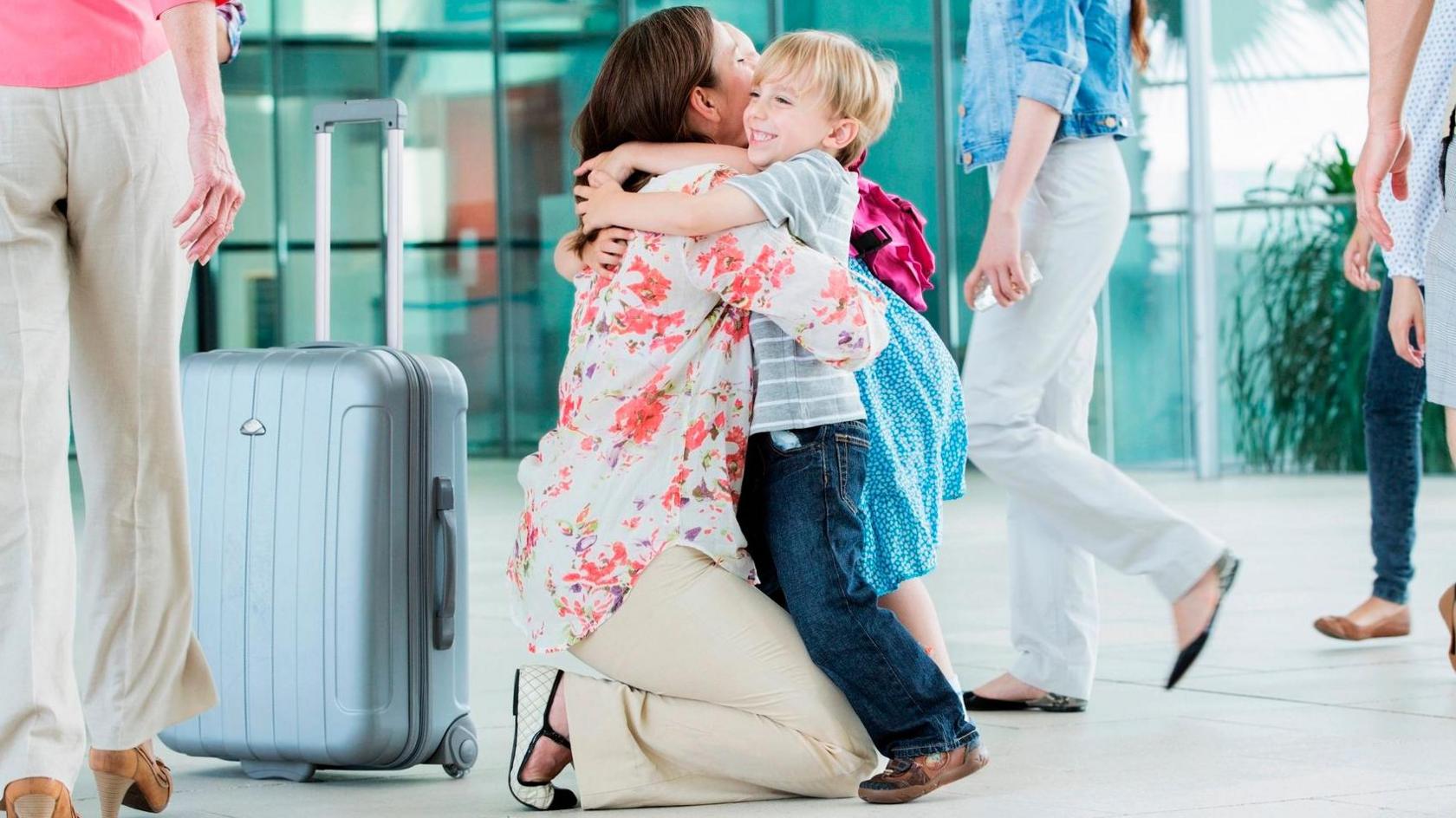 Woman hugging child at airport.