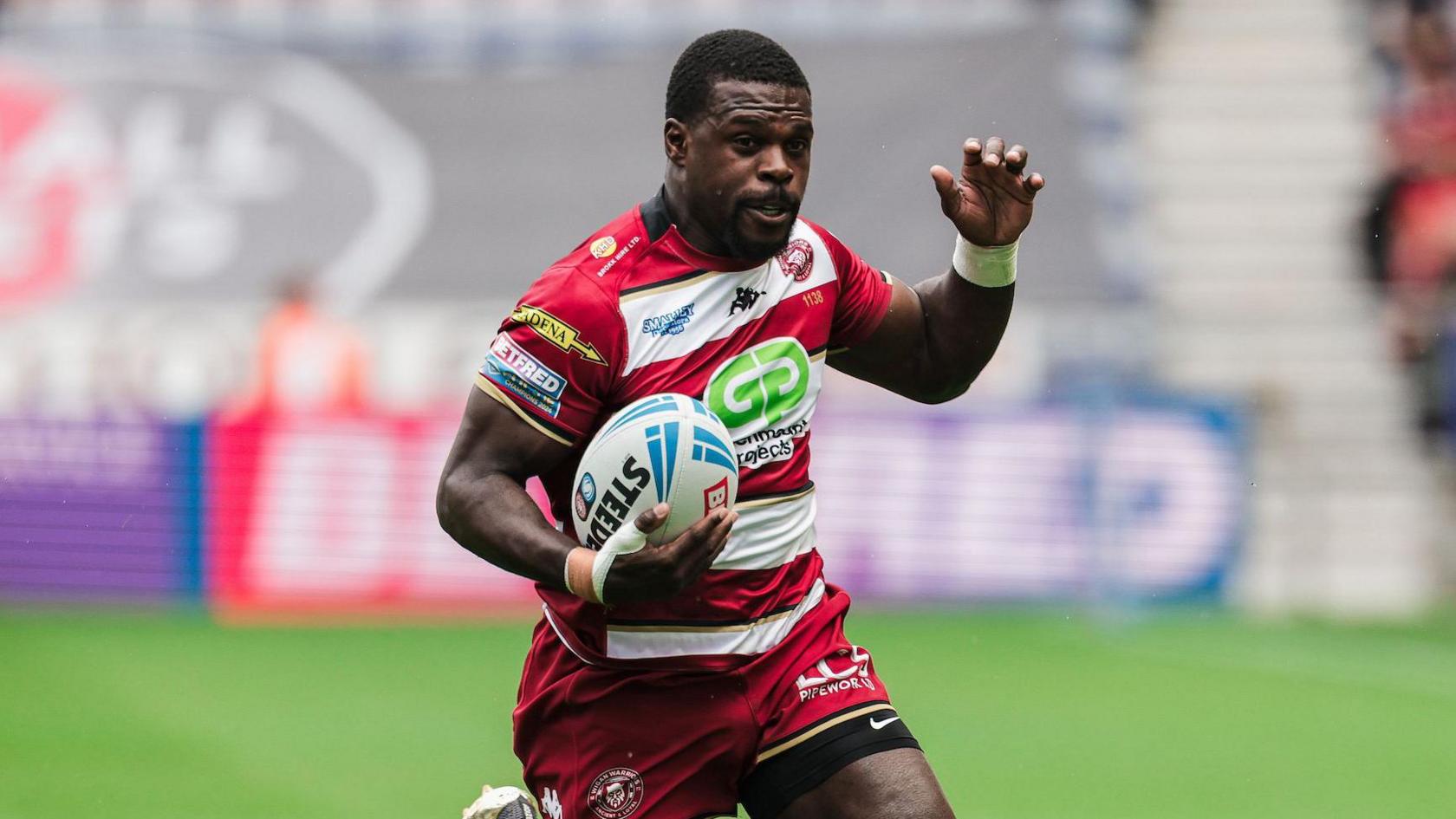 Christian Wade running with the ball in one hand and the other arm slightly raised while playing for Wigan