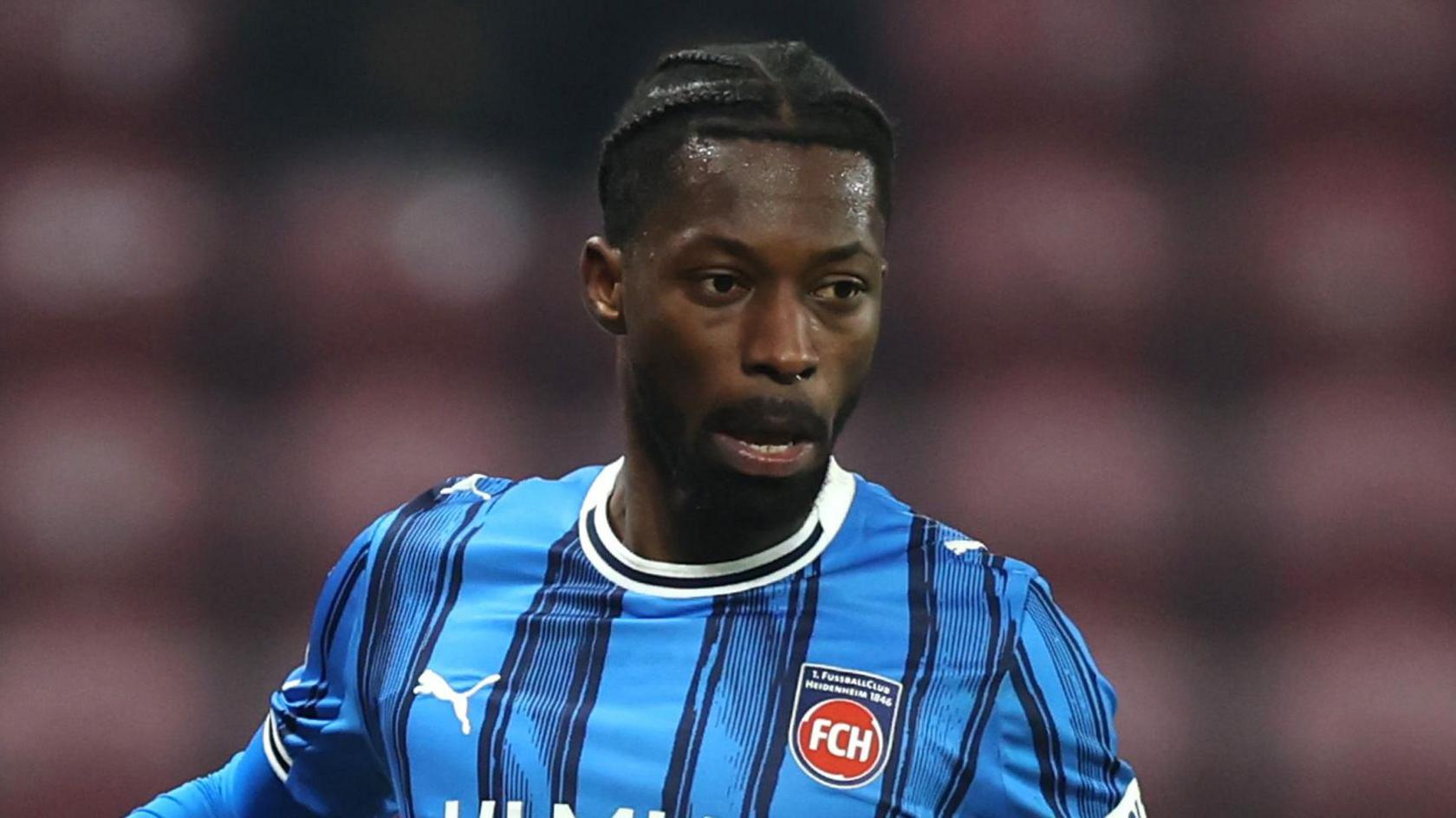 Omar Traore in a blue and black striped FC Heidenheim jersey during a match.