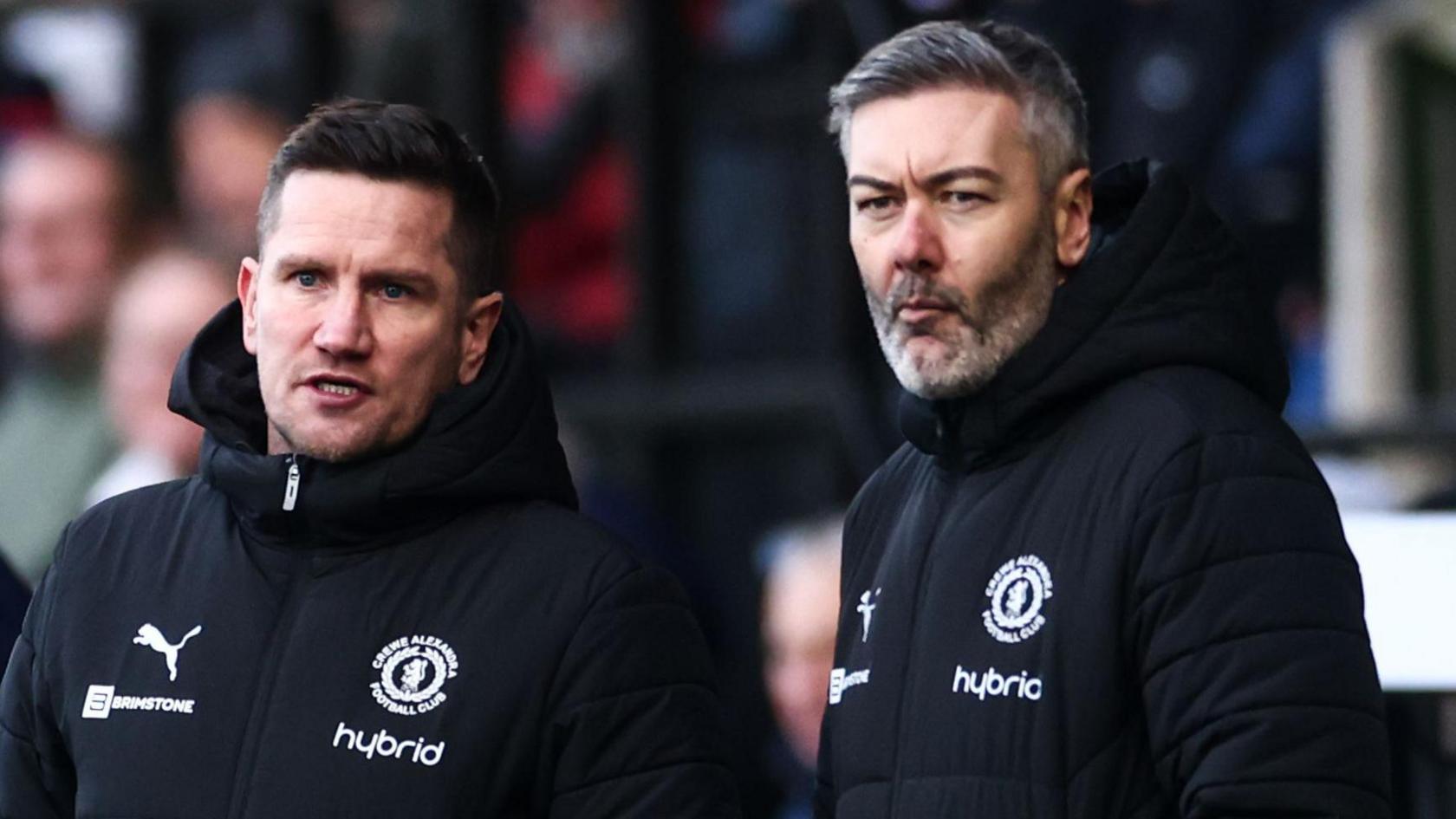 Ryan Dicker is on the right of the picture standing next to Crewe manager Lee Bell as the pair watch on from the touchline