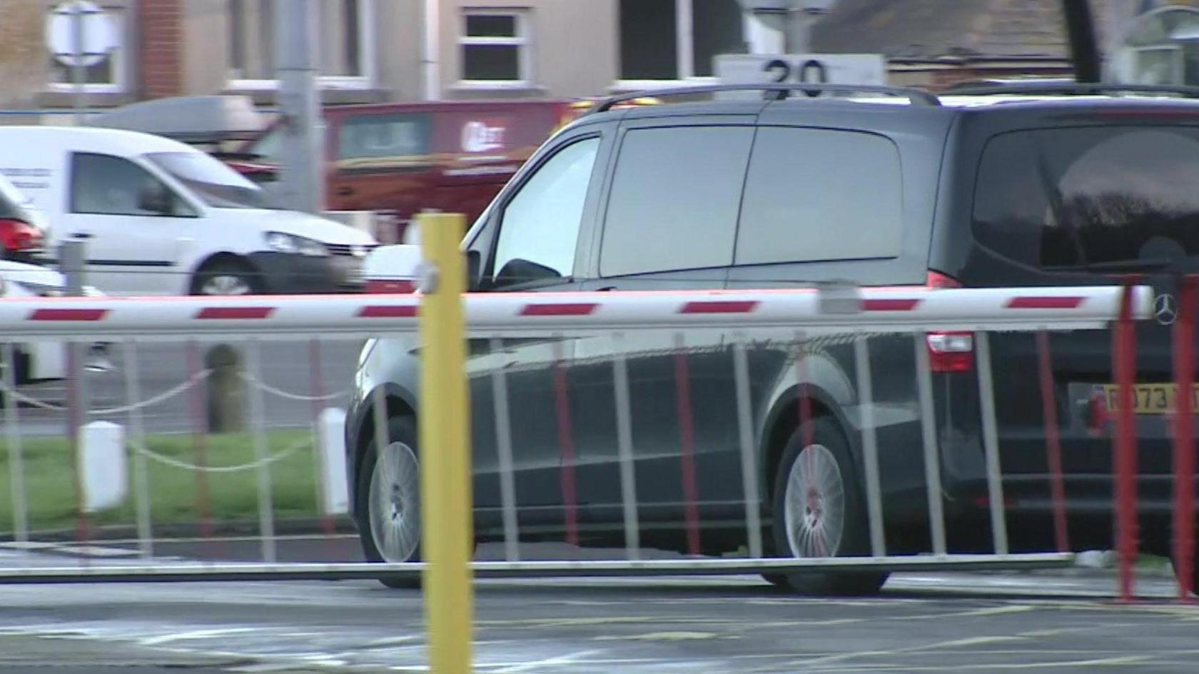 A black taxi driving past red gates.