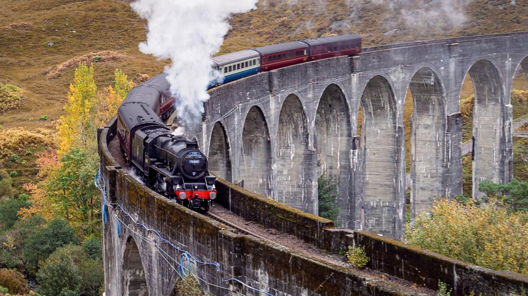 The Jacobite Express steam train crossing the Glenfinnan Viaduct in the Scottish Highlands