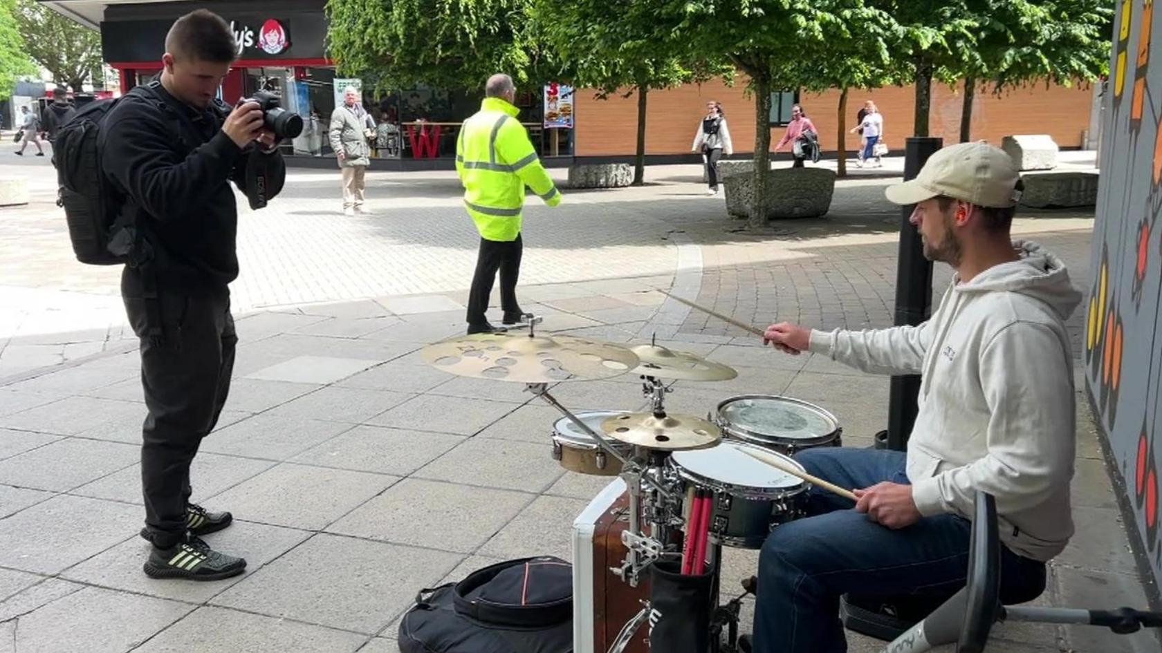 Jamie O'Neill takes a photo of a man playing a drumkit