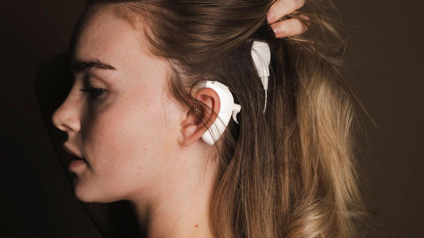 A portrait from the exhibition showing a model holding her hair back to show her ear, after cochlear implant surgery.