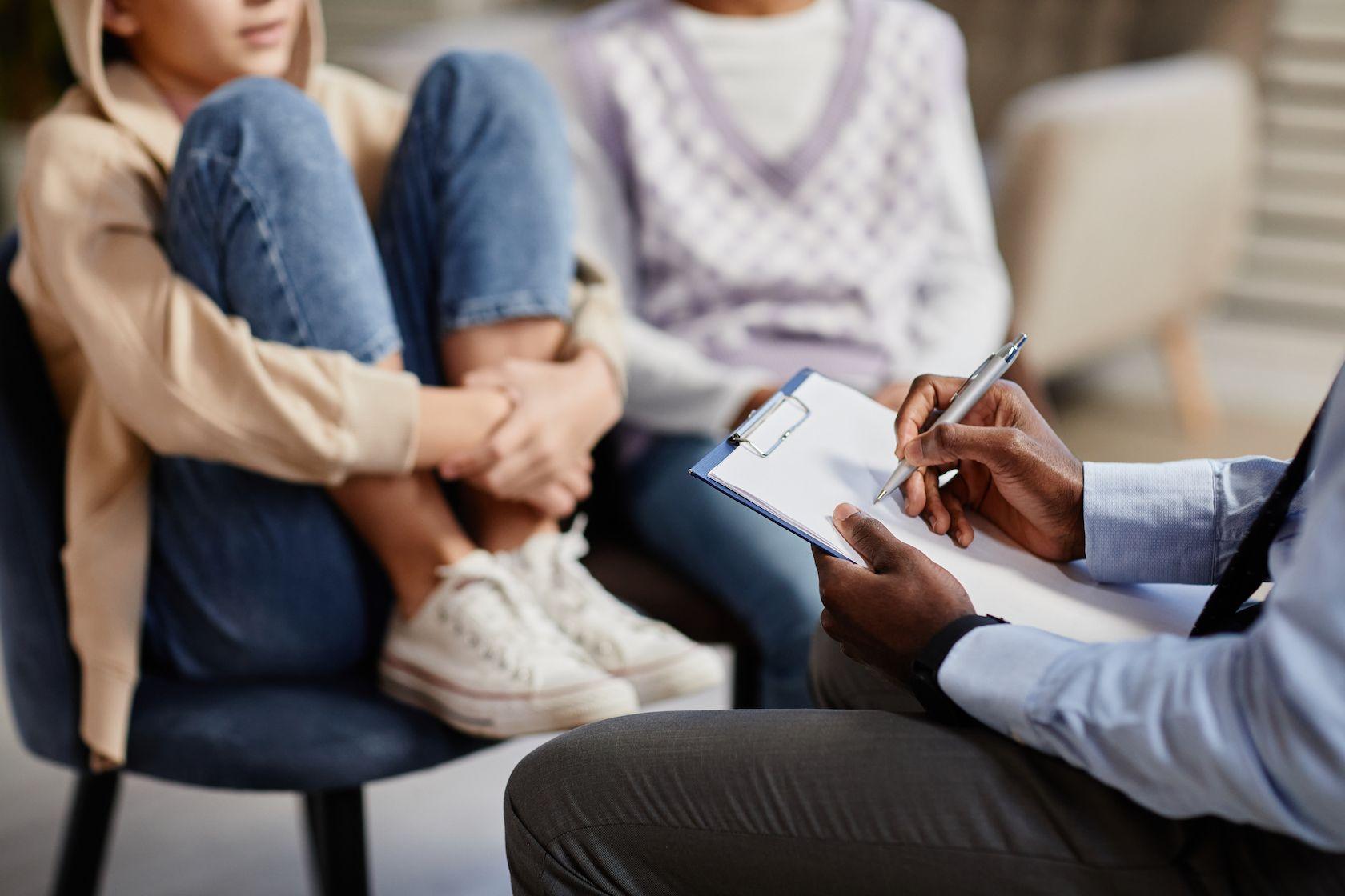 Anonymous young person sits on chair facing a doctor