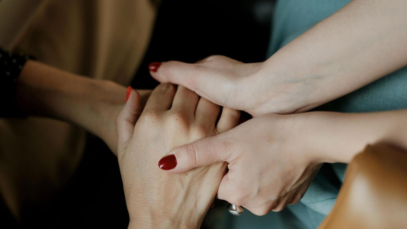 Women hold hands during a support group session.