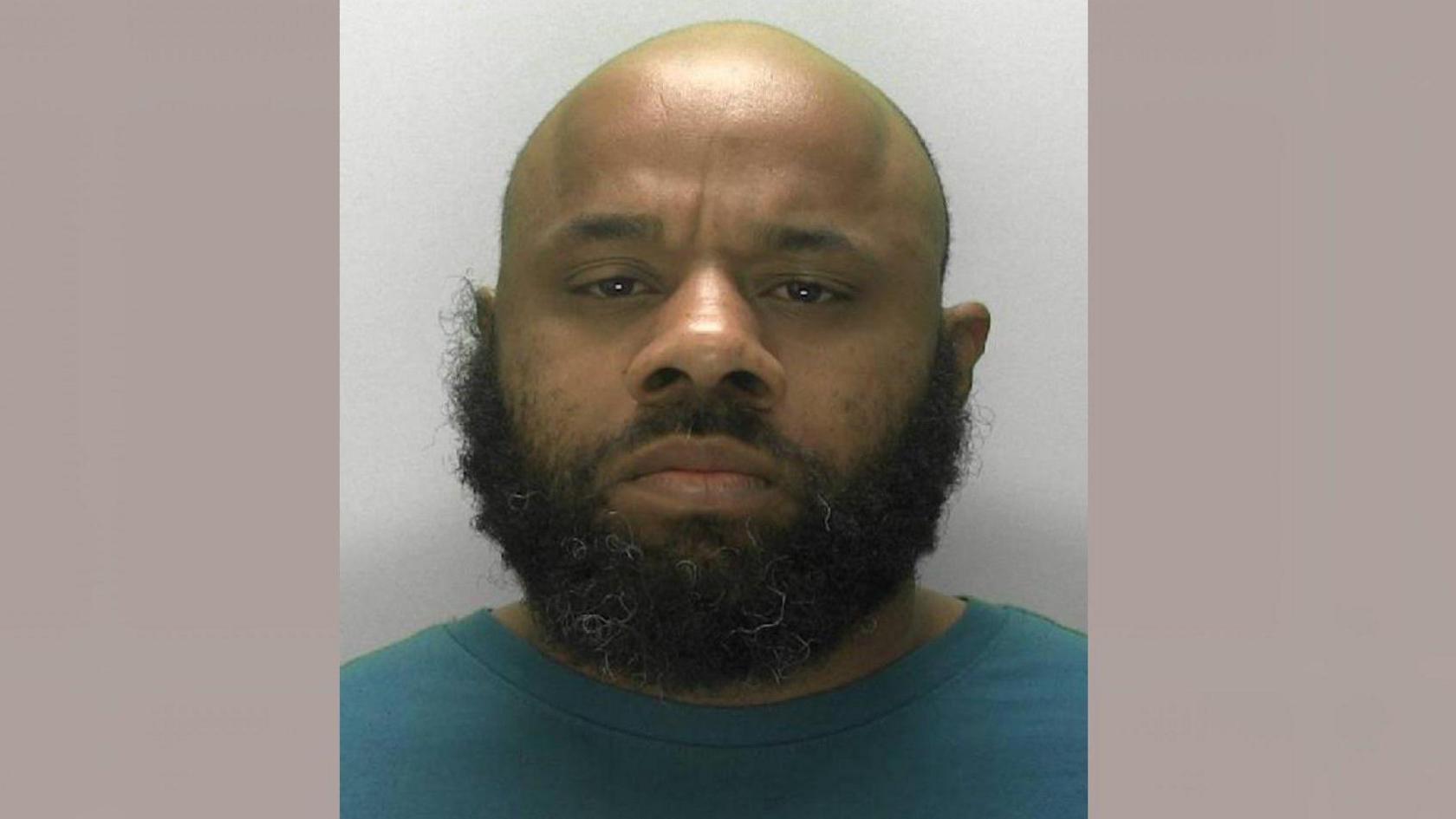 Simeon Bernard is looking at the camera in a police mugshot. He has a bald head and a thick beard.