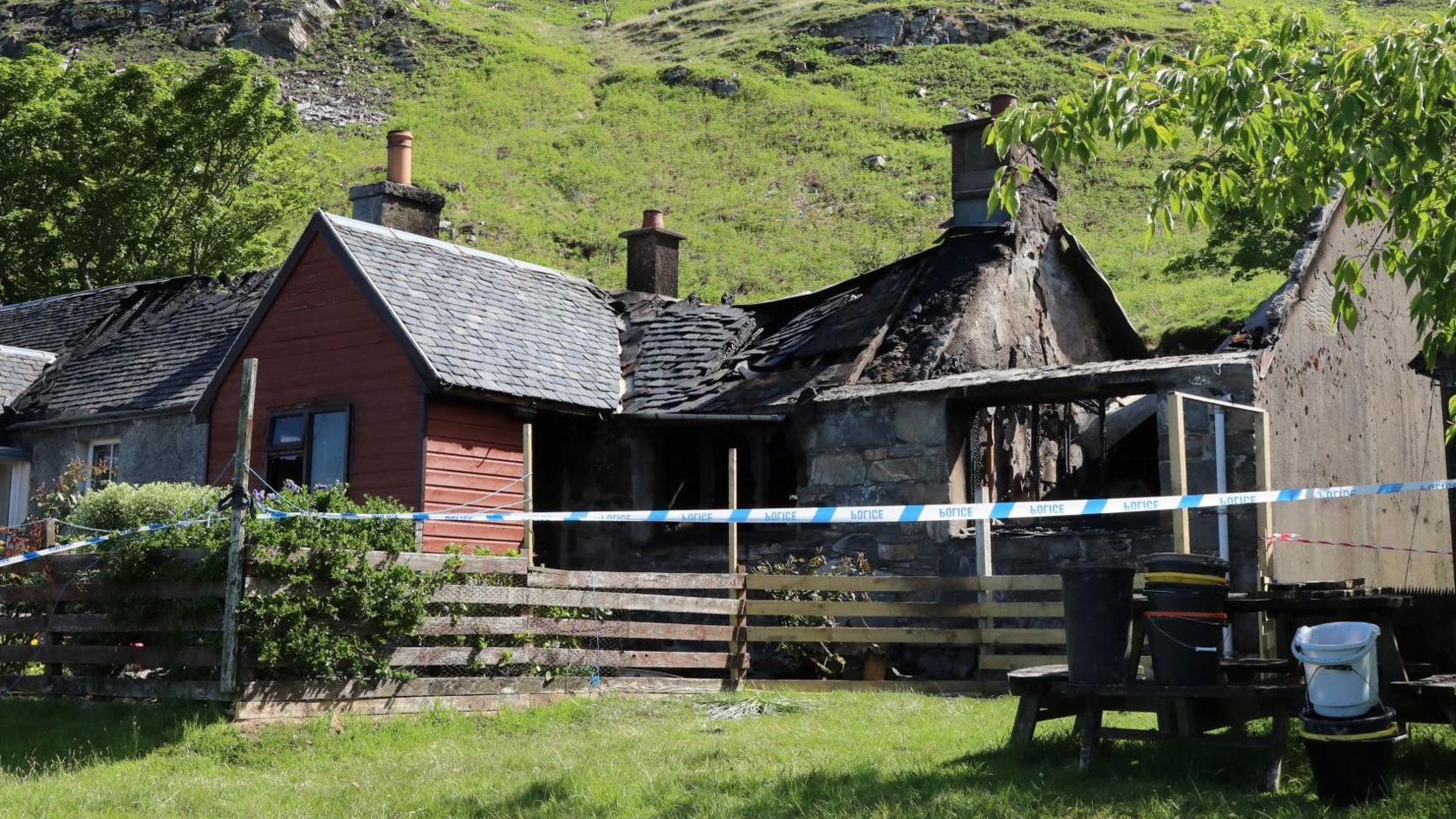 Part of the slate roof of the property has collapsed, while another section of the home has been gutted by the fire. There is police tape in front of the house.