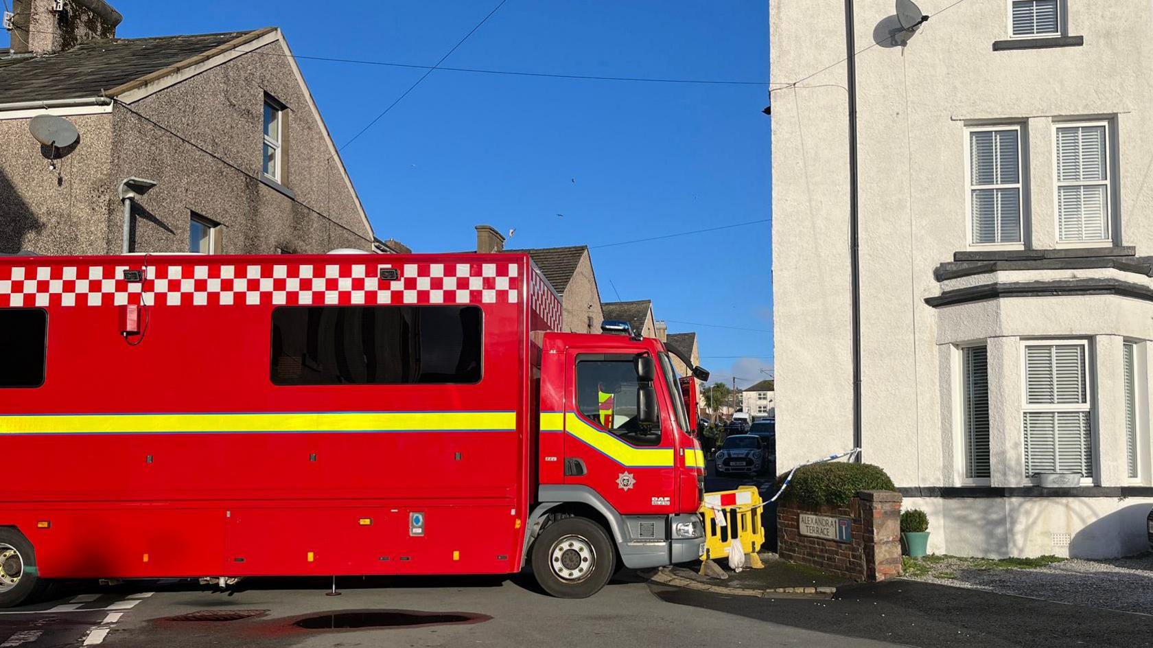 A big red fire truck is parked in front of a street, blocking off the path.