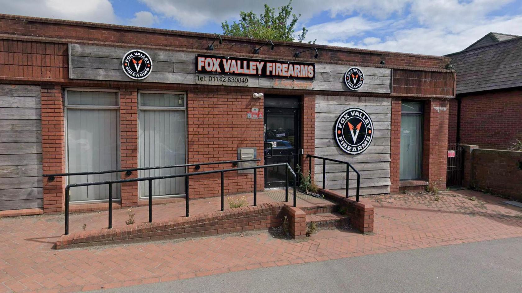 A red brick building that is now a firearms shop.