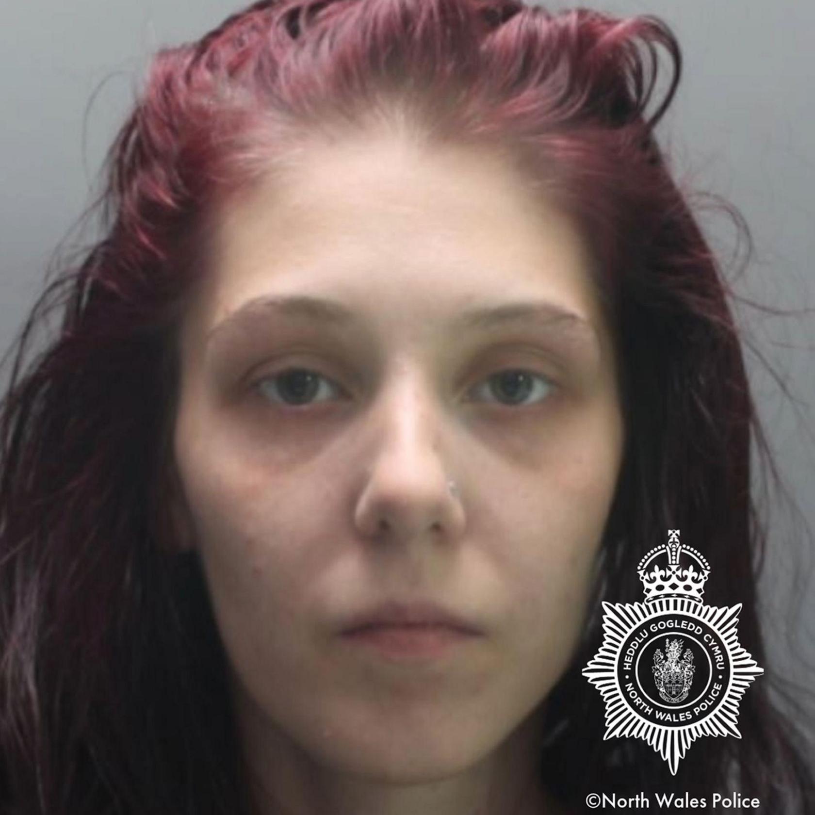 Shannon Ives' mugshot. She is staring at the camera. She has blue eyes, a nose stud and dyed purple hair