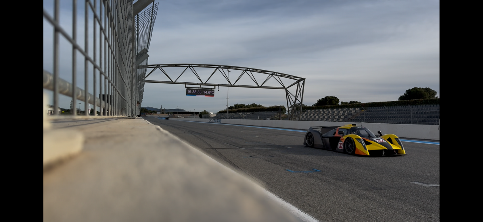 A yellow prototype sports car going down the straight of the Paul Ricard circuit.