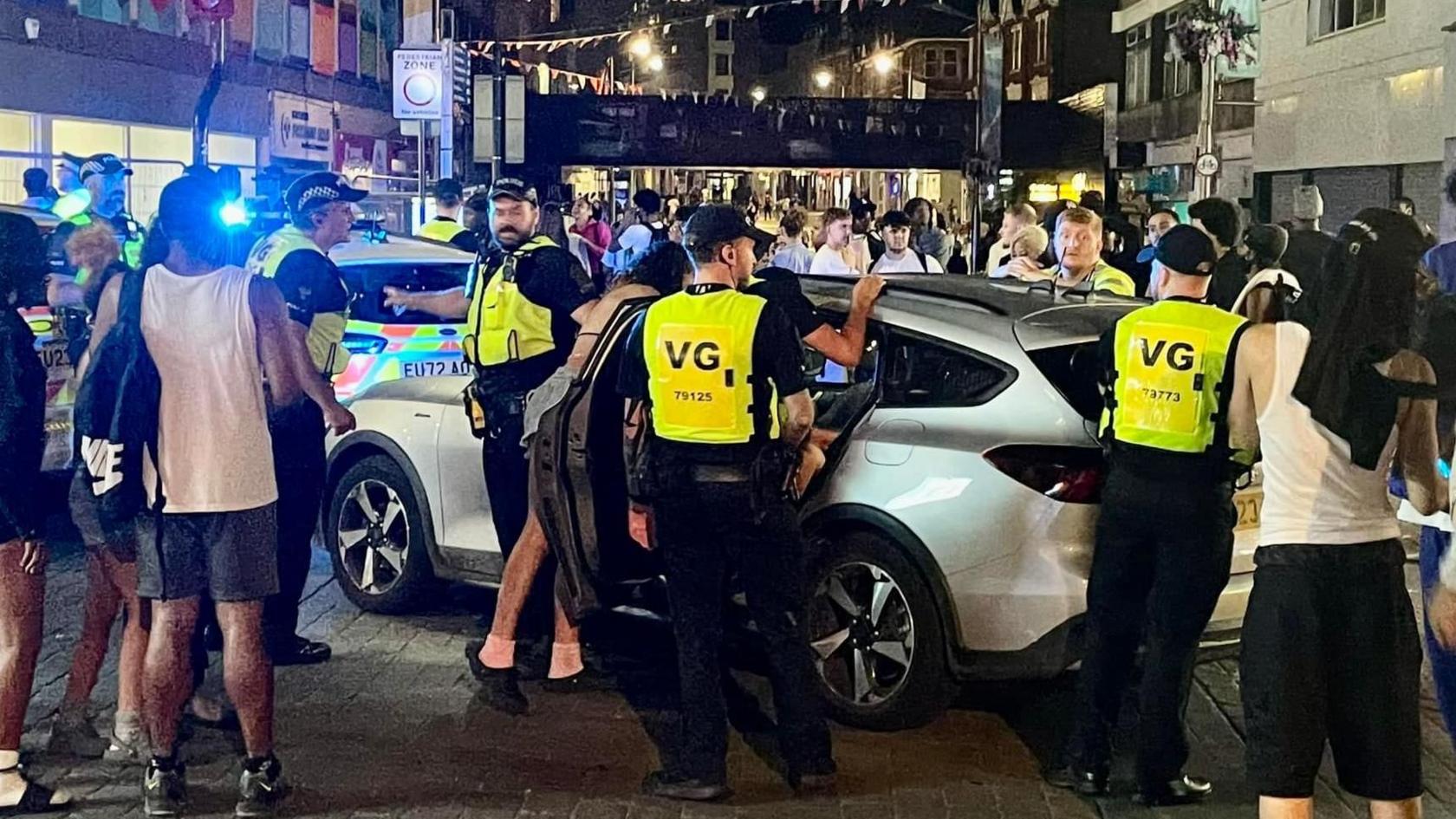 Police cars, men wearing hi-vis jackets. Everyone is surrounding a car