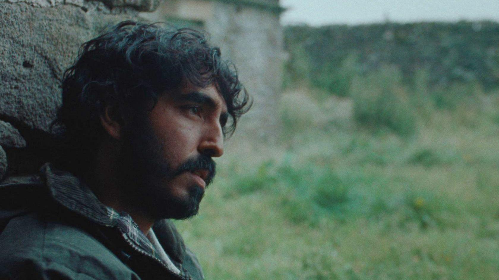 A man sat against a wall staring ahead 