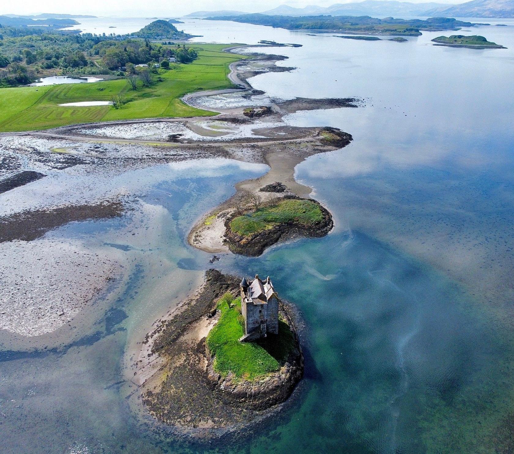 Drone image of a castle on an island among clear water