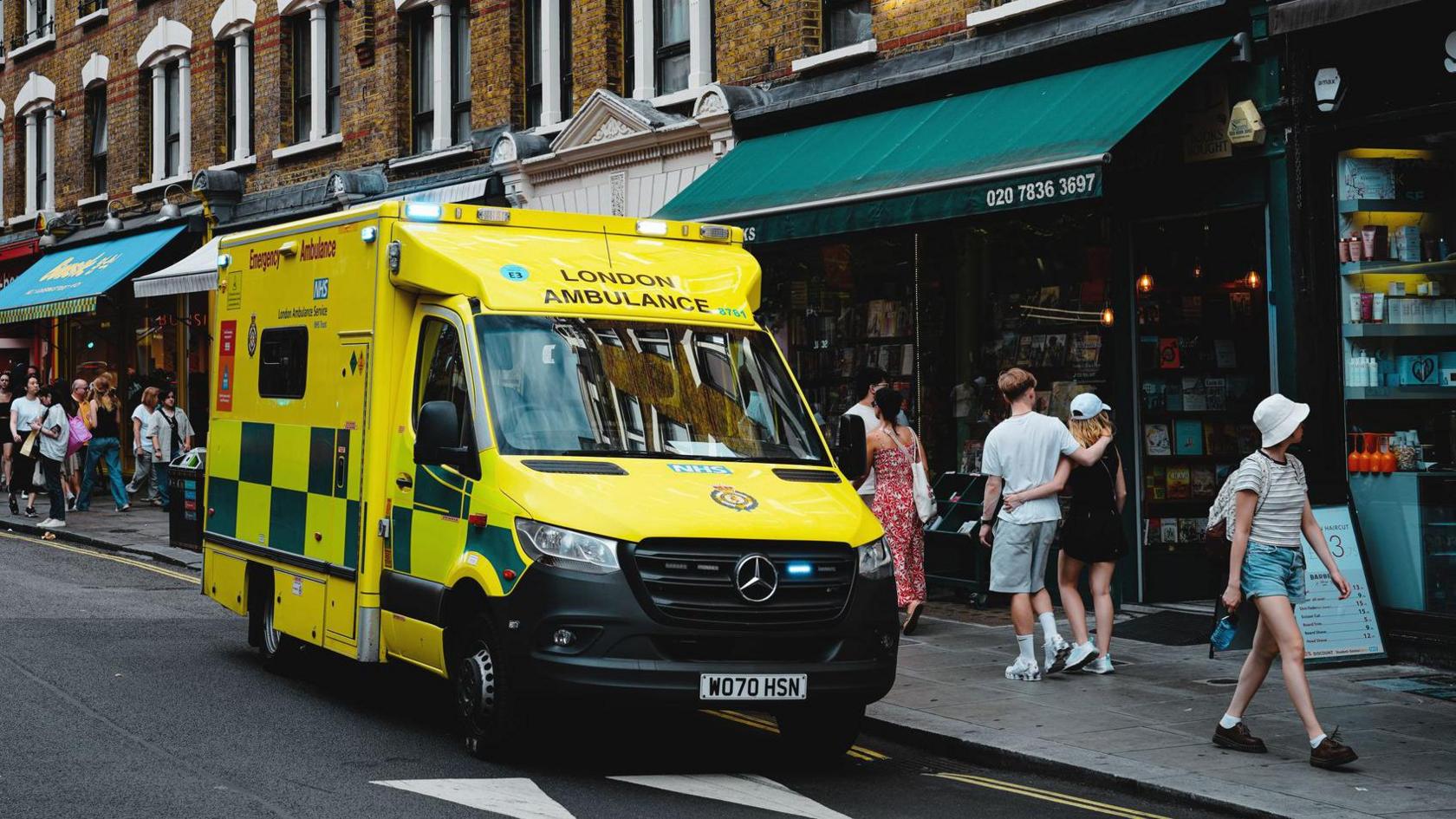 An NHS ambulance is parked on Charing Cross Road, London.