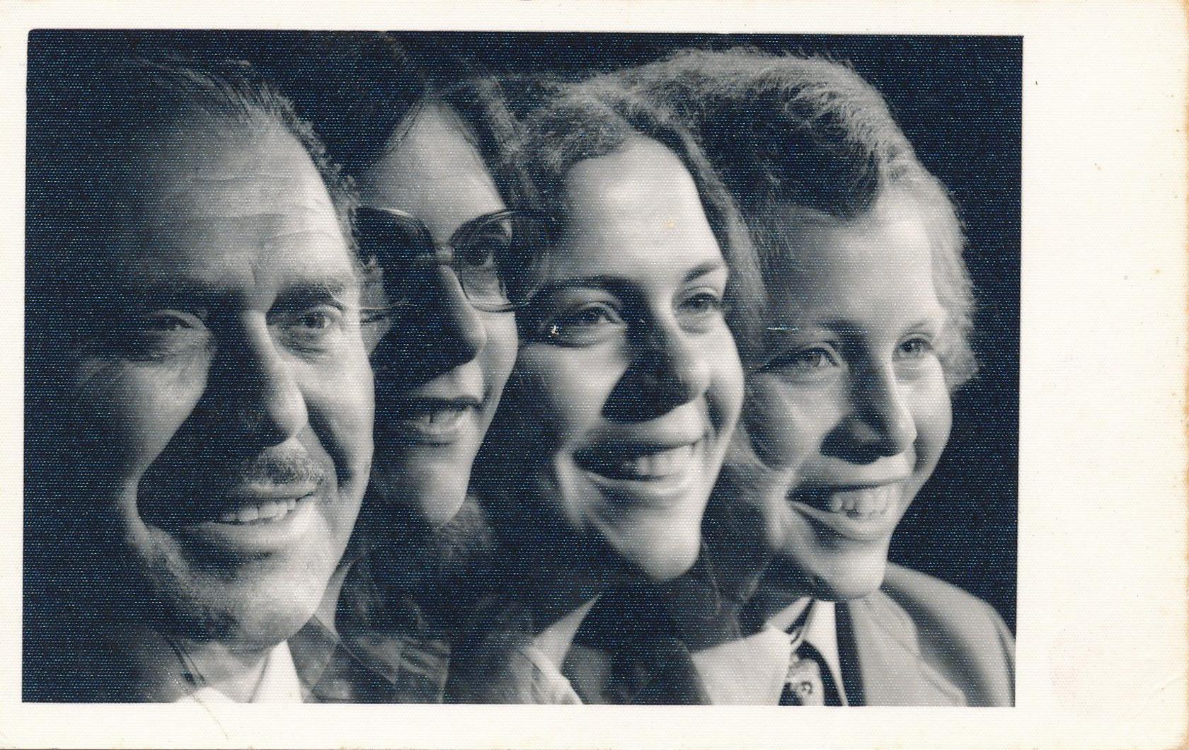 A studio photo of four people - a man, woman, girl and boy - smiling. It is in black and white