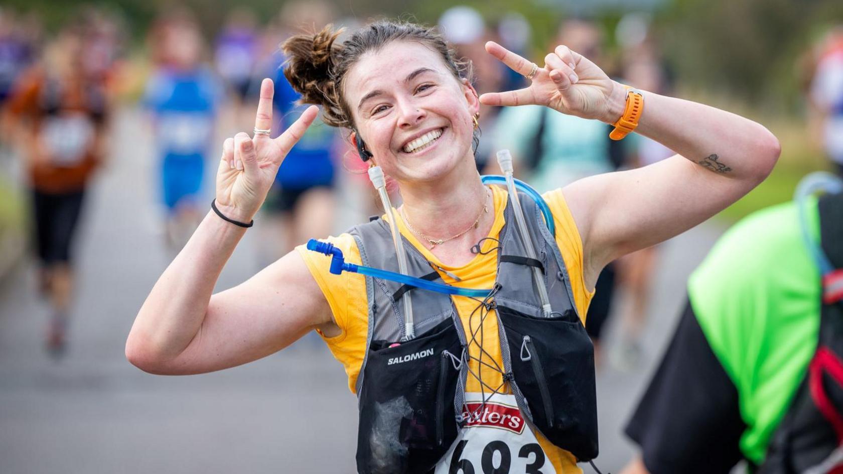 A marathon runner makes V victory signs with her fingers