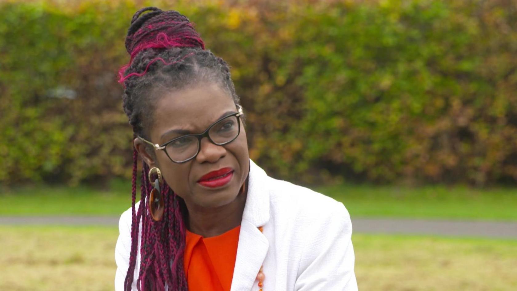 Dr Ebun Joseph wearing a white blazer and a red top 