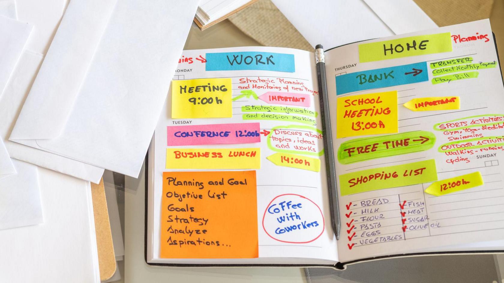 Person is organizing their work and personal agenda in a notebook at home, using sticky notes and colorful markers to plan their week, surrounded by envelopes, a smartphone, and a notepad