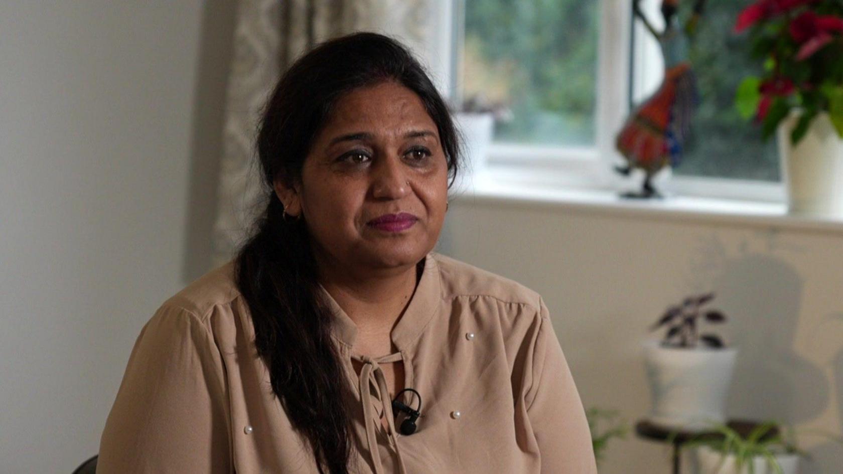 Seema Misra wearing a brown chiffon top sitting in her living room