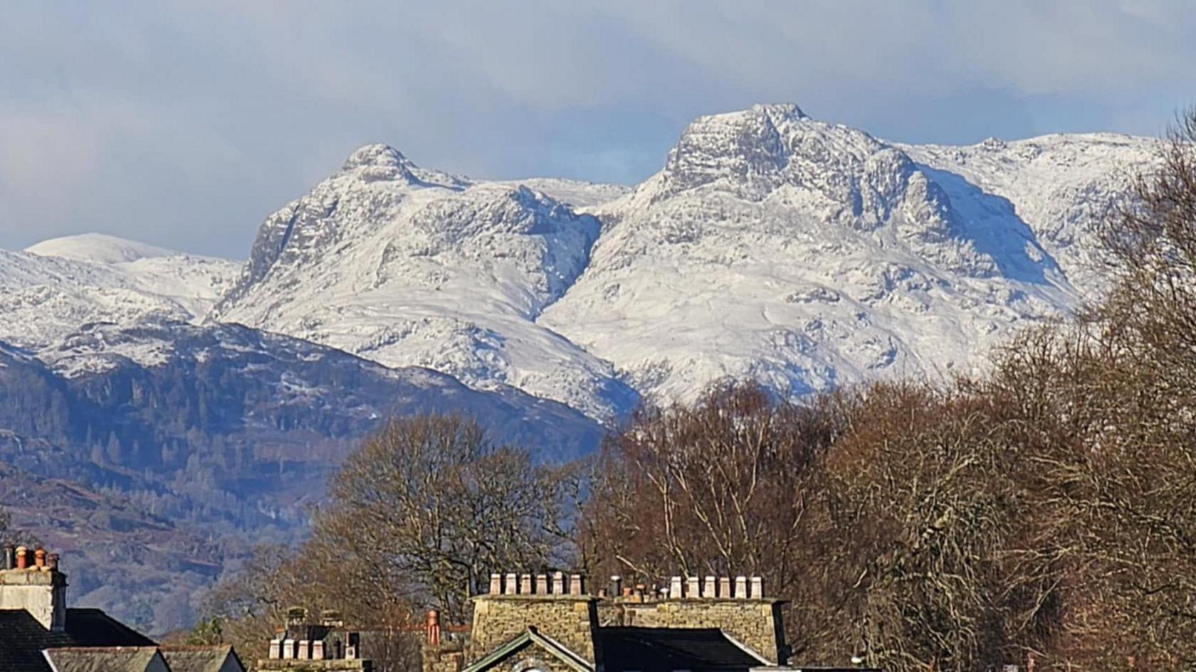 The Langdale Pikes which are covered in snow in the Lake District. There are two prominent knobbly peaks which look picturesque.