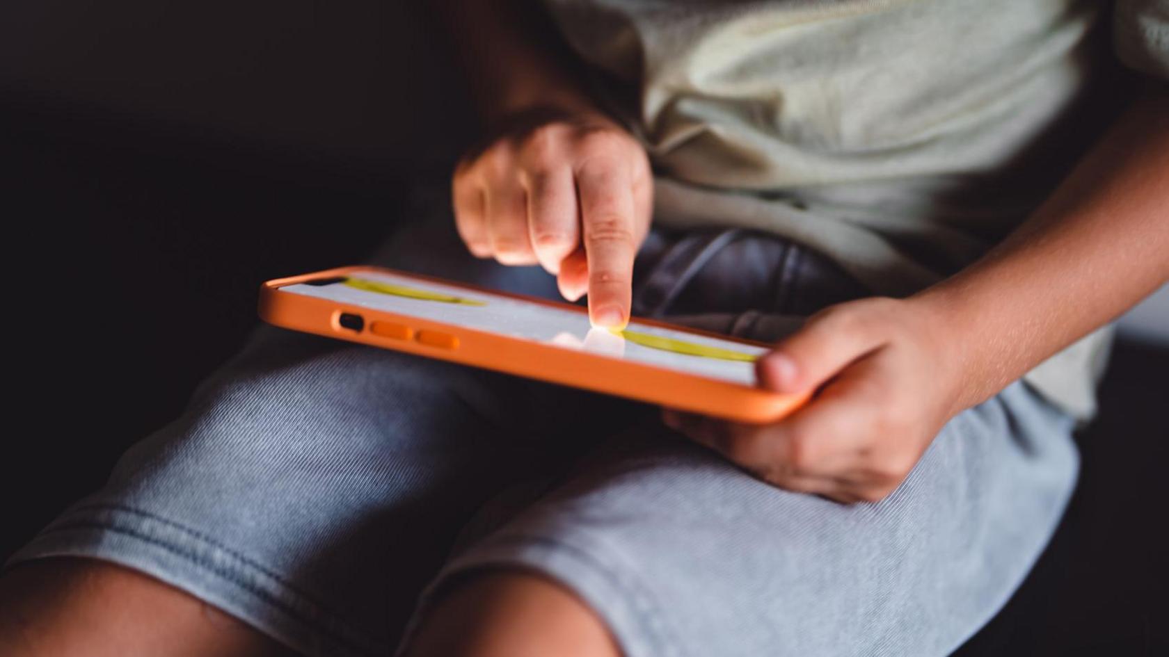 A child tapping on a phone in landscape mode