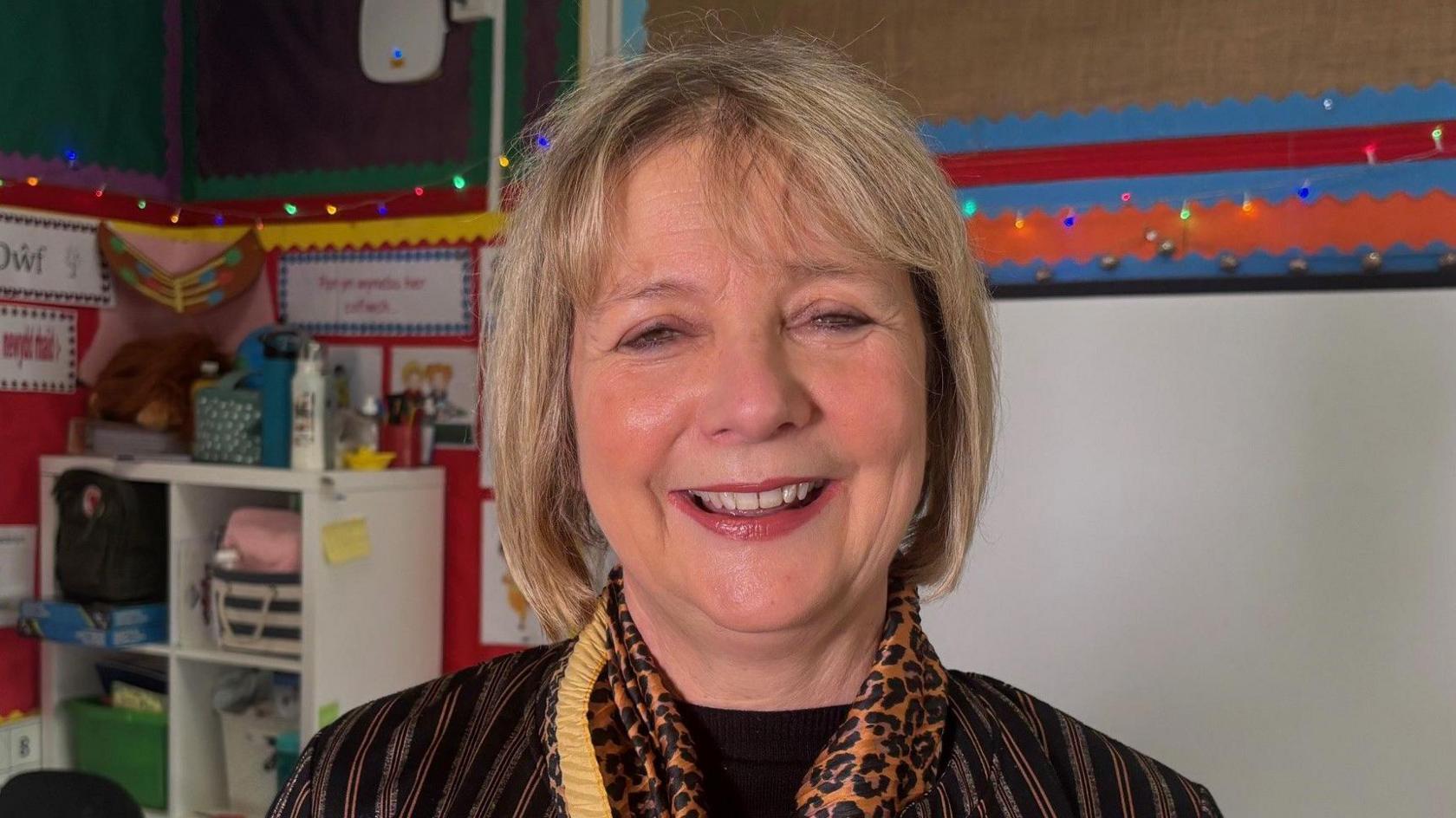 Head teacher Gwenan Davies Jones. She is smiling and wearing a vertically striped top and leopard print scarf 