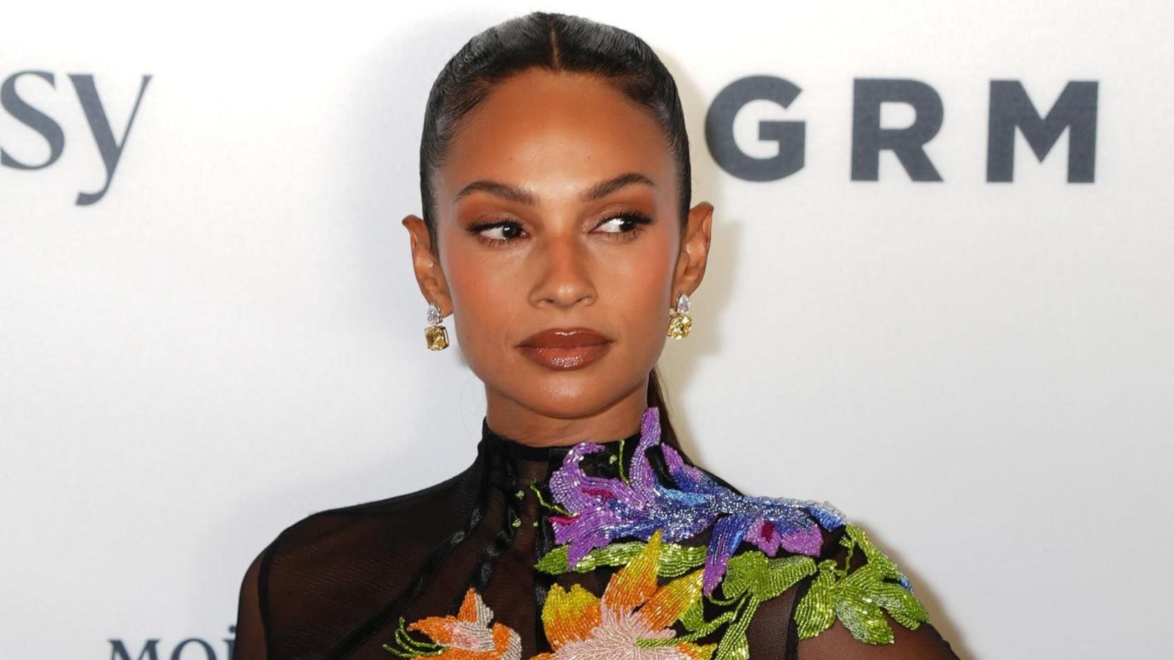 Alesha Dixon at the GRM Gala in London. Alesha wears her hair slicked back in a long pony tail and wears a high-necked black dress embroidered with colourful flowers