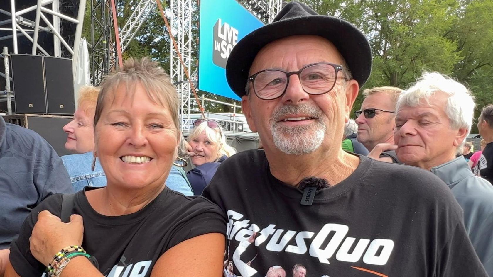 Michelle and Peter Moore, both wearing Status Quo tops and smiling amongst a crowd