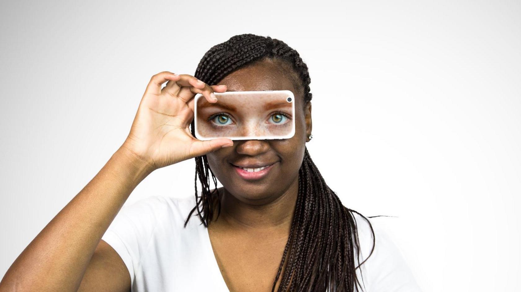 Lady holds up her phone in front of her eyes - the phone is displaying an image of her eyes.