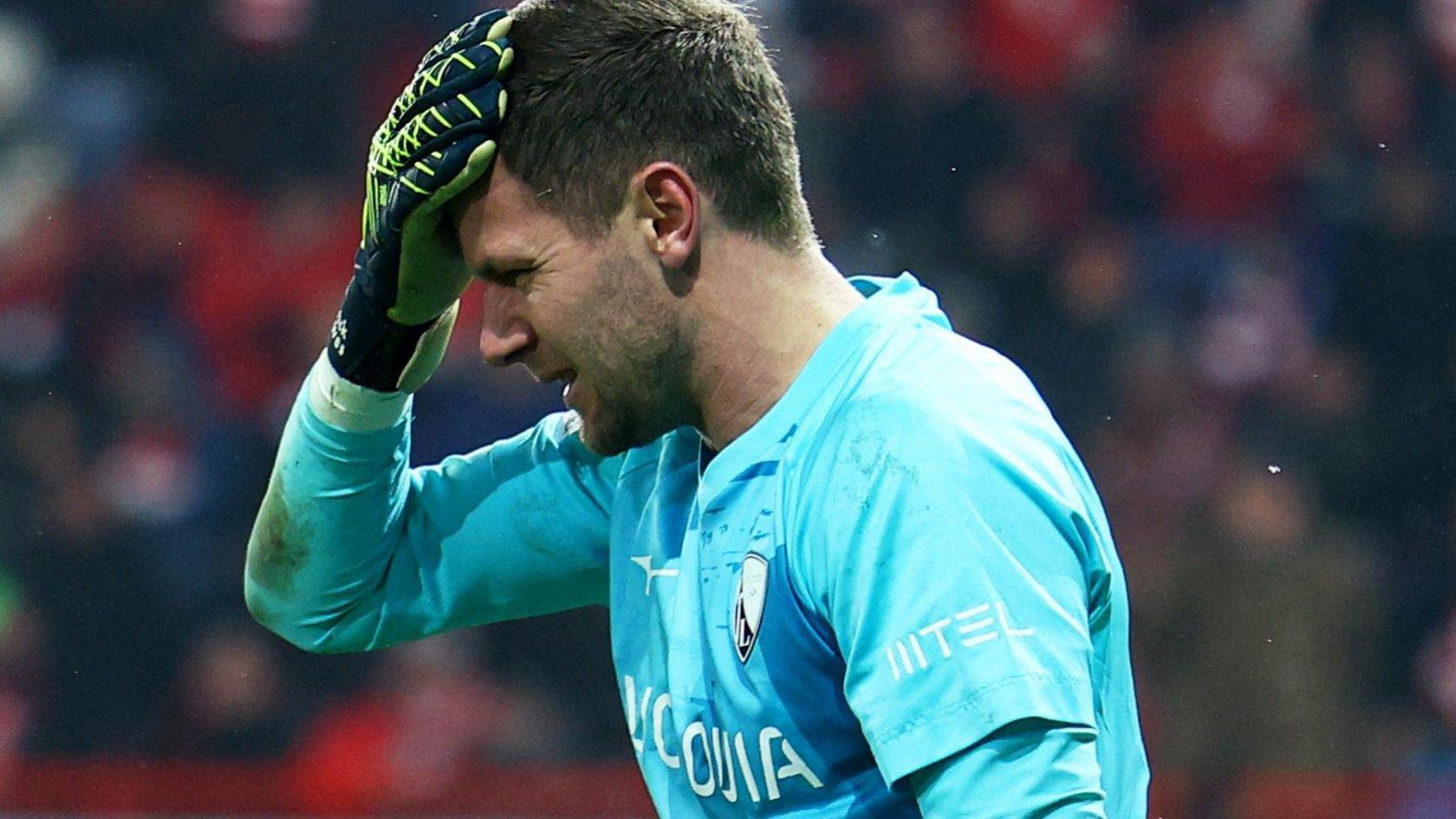 Bochum goalkeeper Patrick Drewes grabs his head after being hit by an object thrown from the crowd in their Bundesliga game at Union Berlin