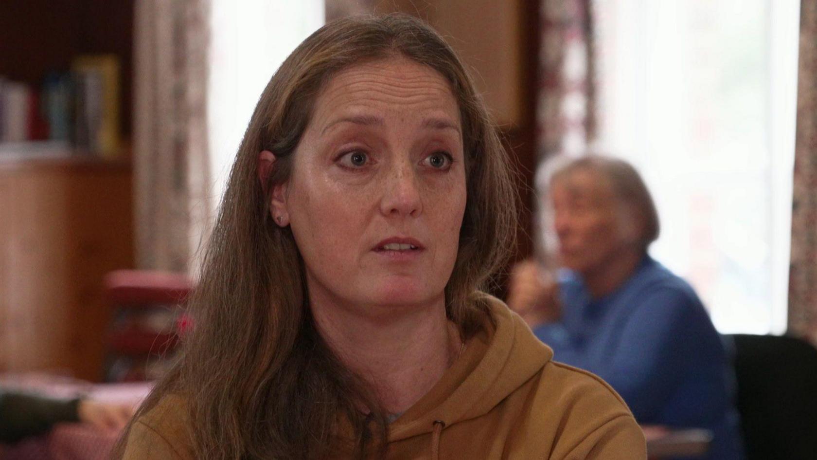 Aysha Hawcutt has long light brown hair and is photographed in a light brown hoodie.