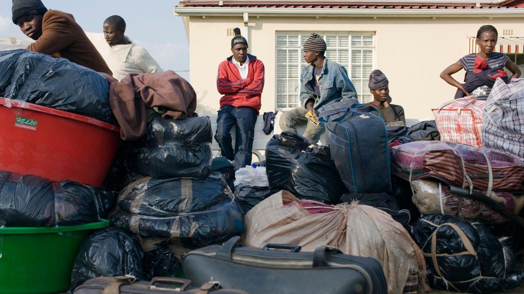 African nationals fleeing South Africa with their luggage in front of them 