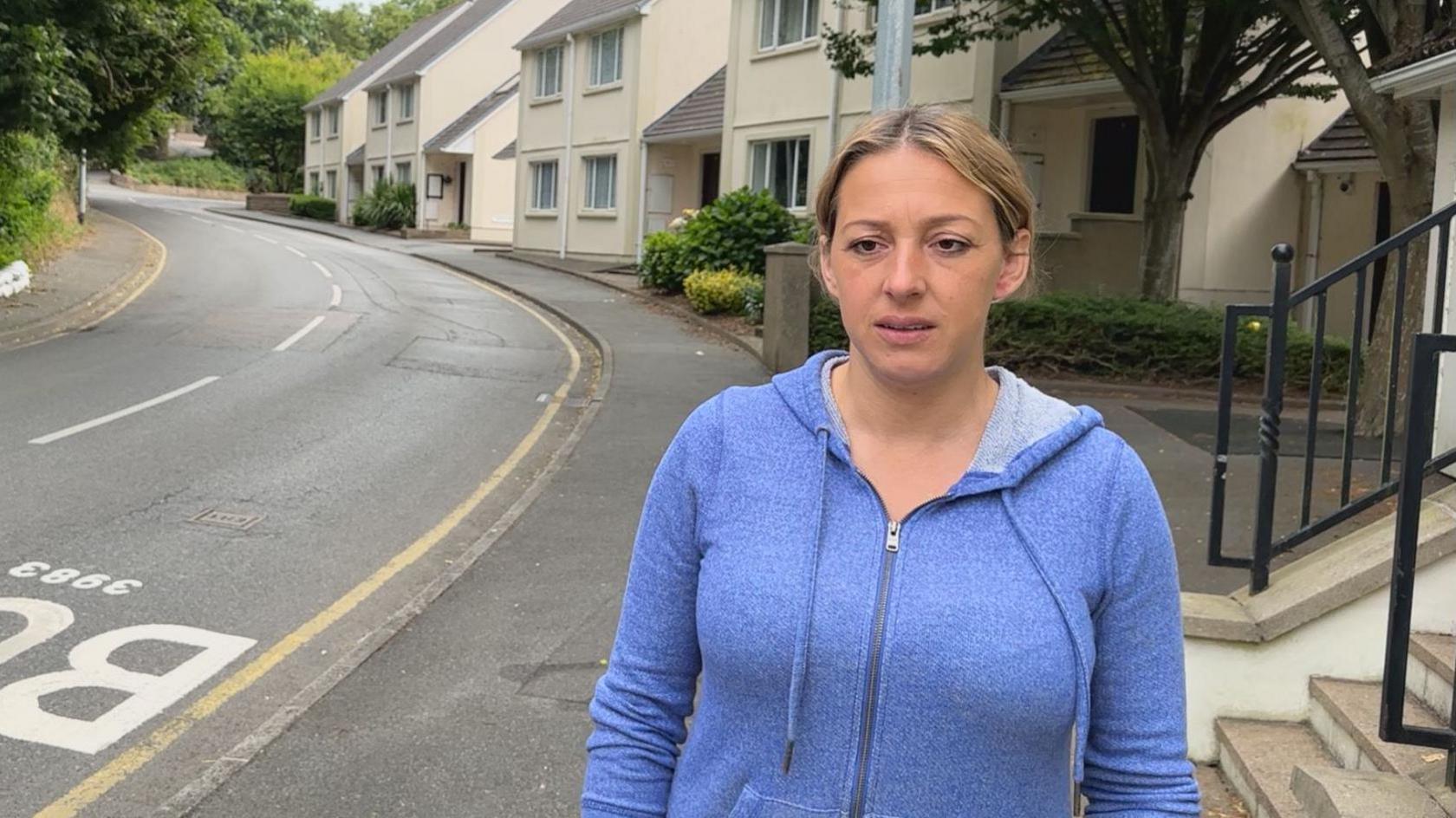 Woman standing outside her home with bus stop in view