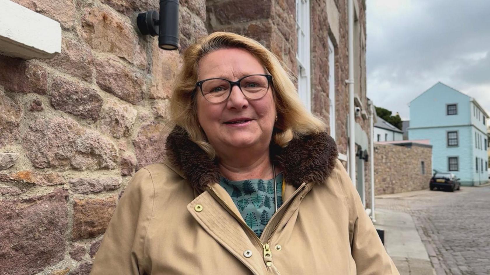 A blonde 60 year old woman stood on Alderney’s high street 