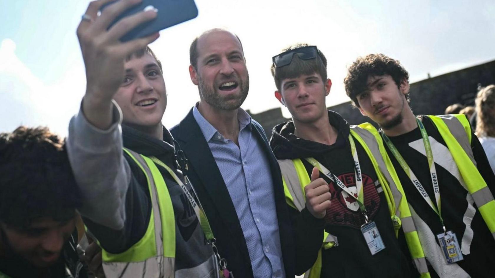 A group of three young men posing for a selfie with the Duke of Cornwall.