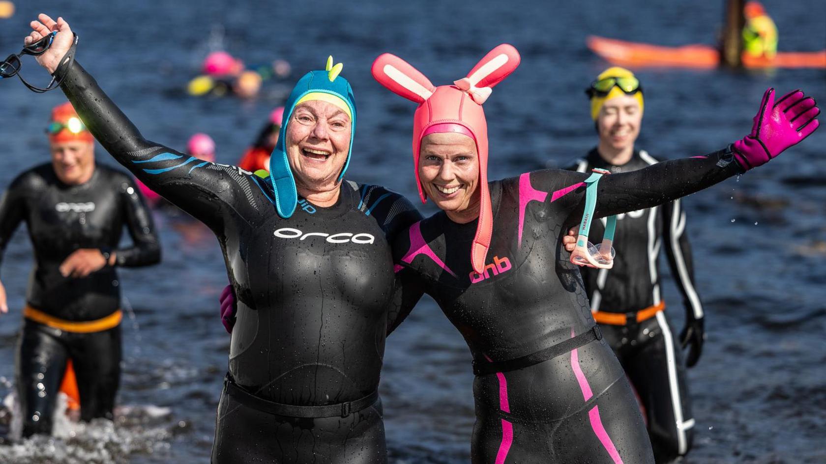 Two swimmers, one with bunny ears, in wet suits after completing the Kessock Ferry Swim