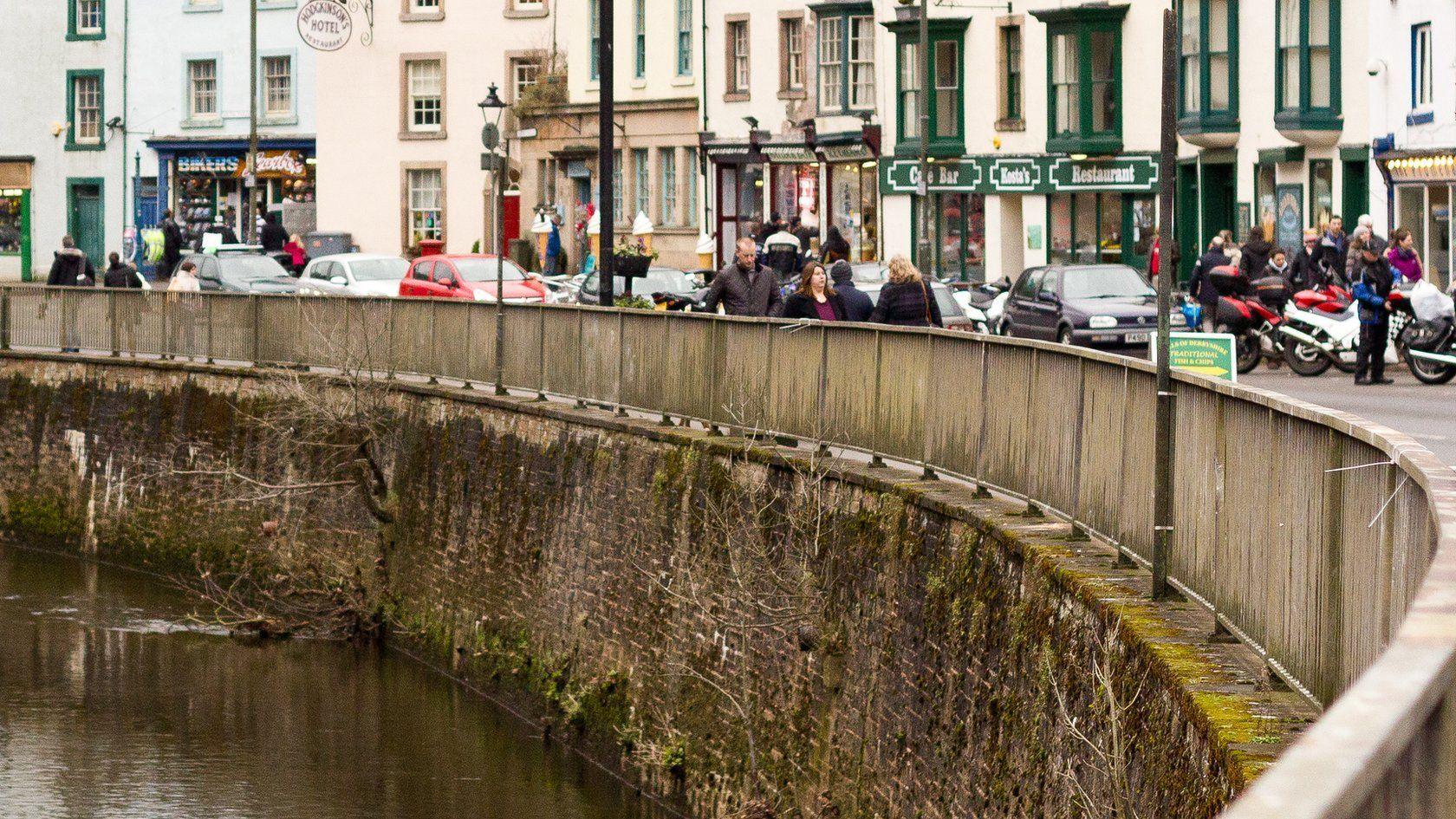 People walking through Matlock Bath with shops, amusement arcades and bikers visible