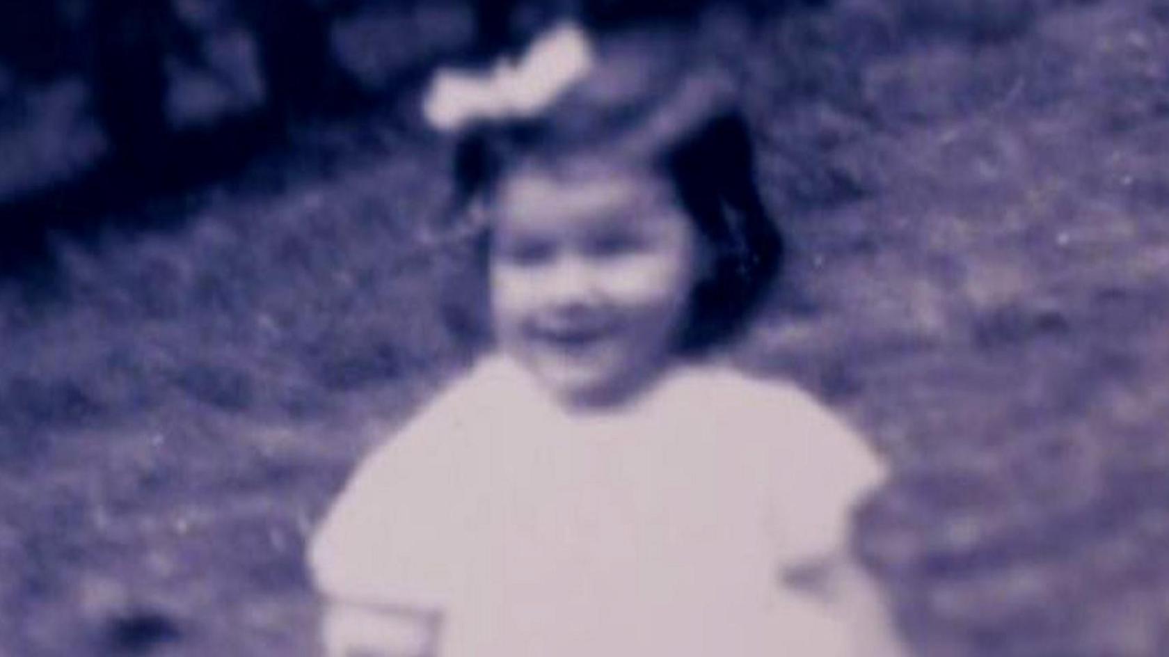 Young Gladys Johnston sitting down. She has a bow in her hair