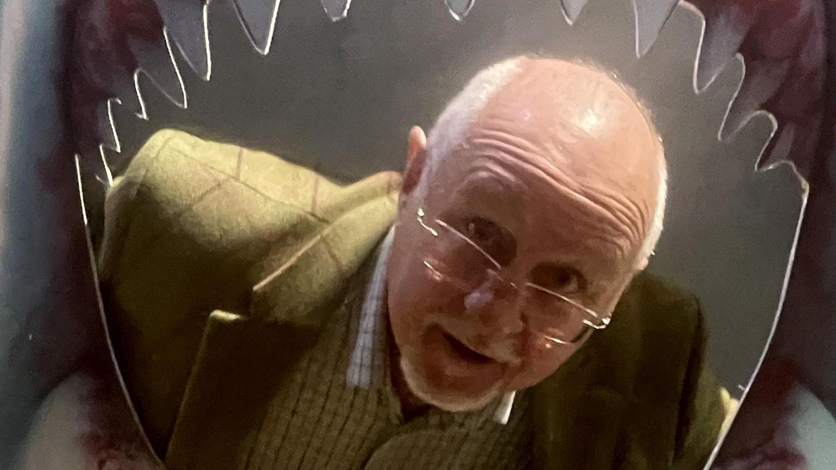 Stephen Rivers, director of Kudos Memorabilia, putting his head thrown a large Jaws poster, which depicts a large, open shark mouth