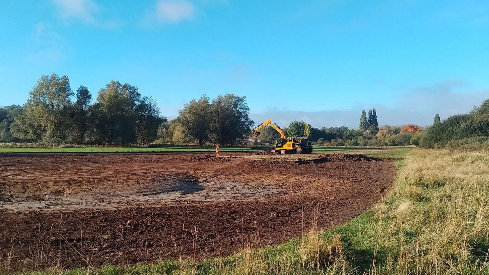 A large amount of land and a large yellow digger in the corner.
