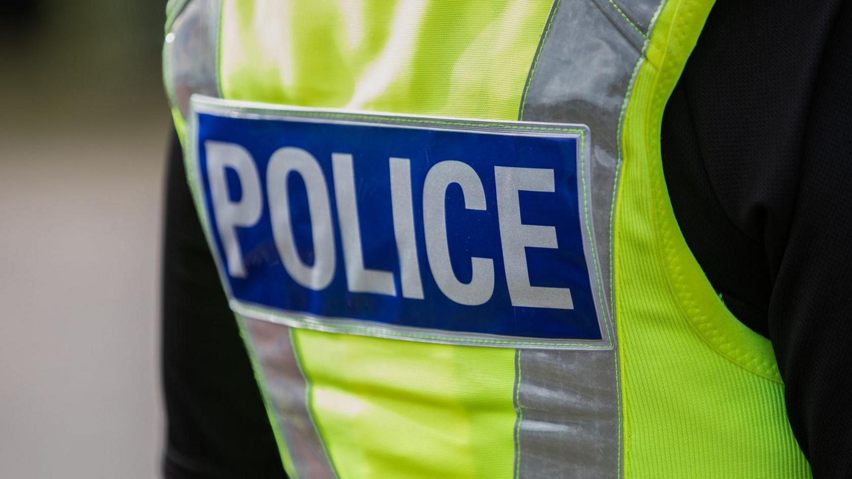 The back of a police officer wearing a hi-vis jacket with "POLICE" written on it