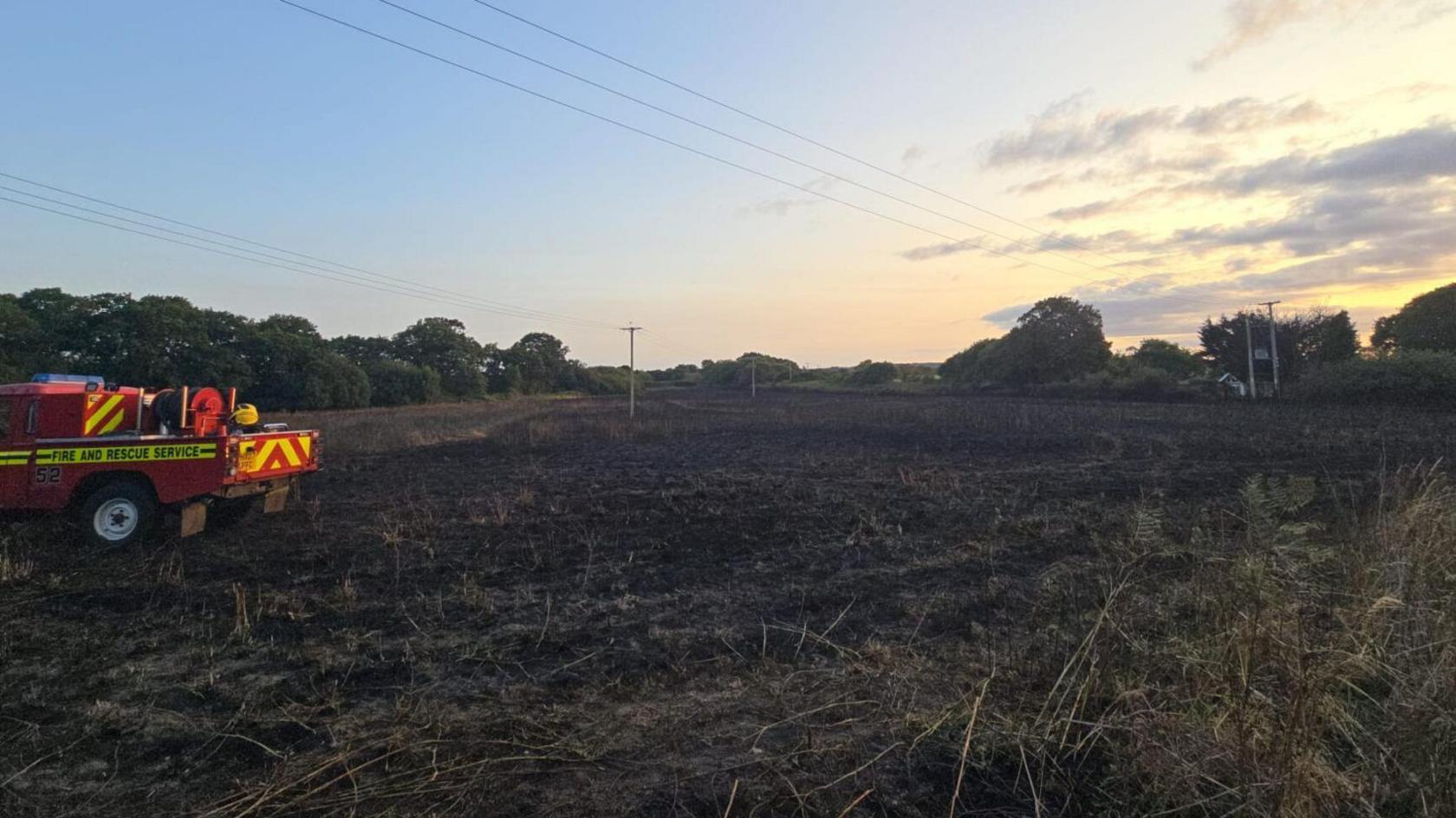 Fire appliance in afield charred by fire.