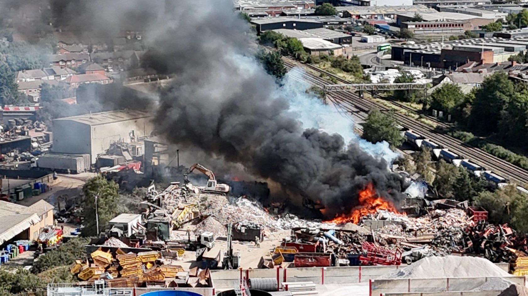 Drone shot of flames and smoke coming from an industrial yard.