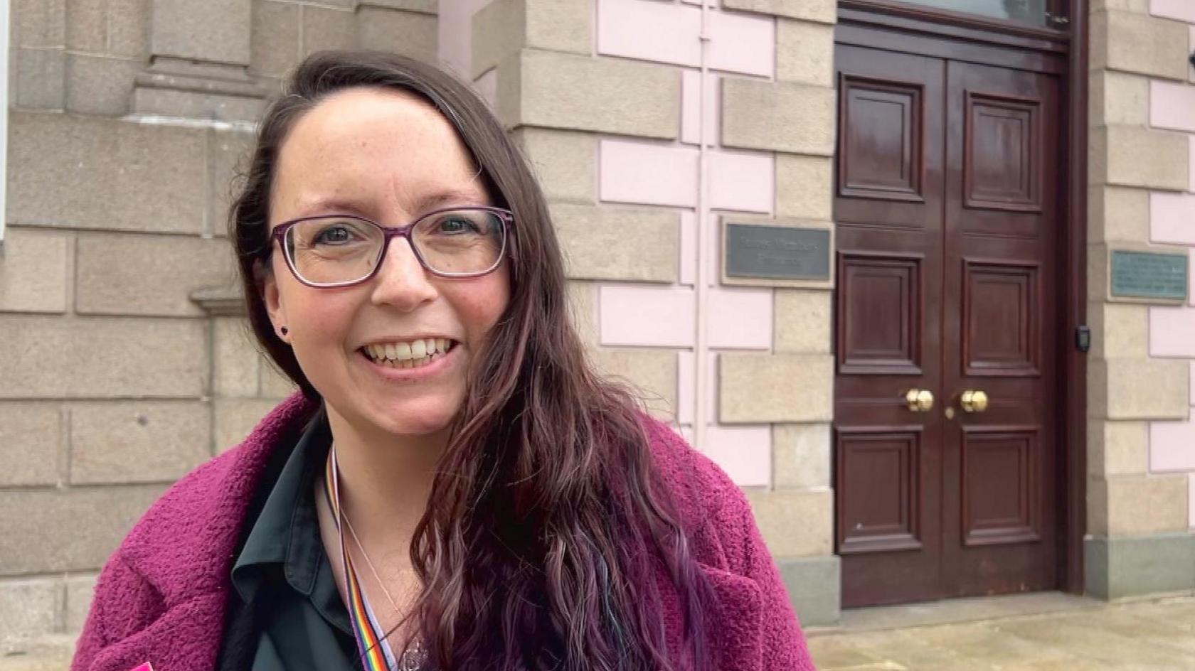 Deputy Louise Doublet standing outside the members' door to Jersey's States Assembly.