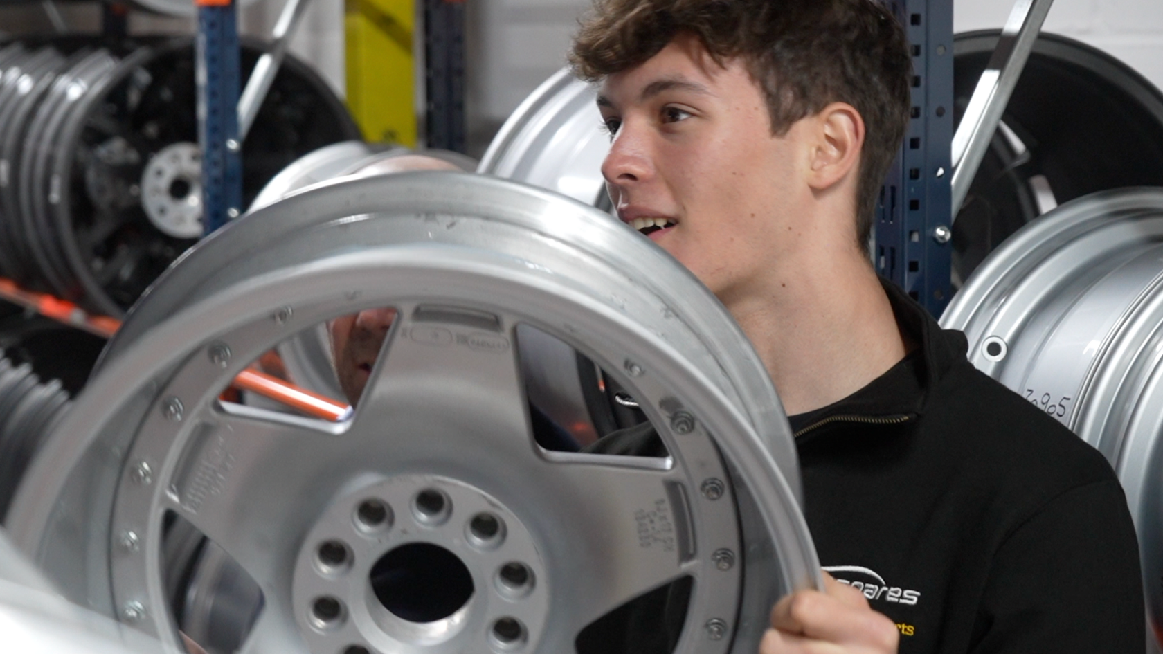 Oliver Bearman holding a wheel during a visit to Essex sponsor Eurospares