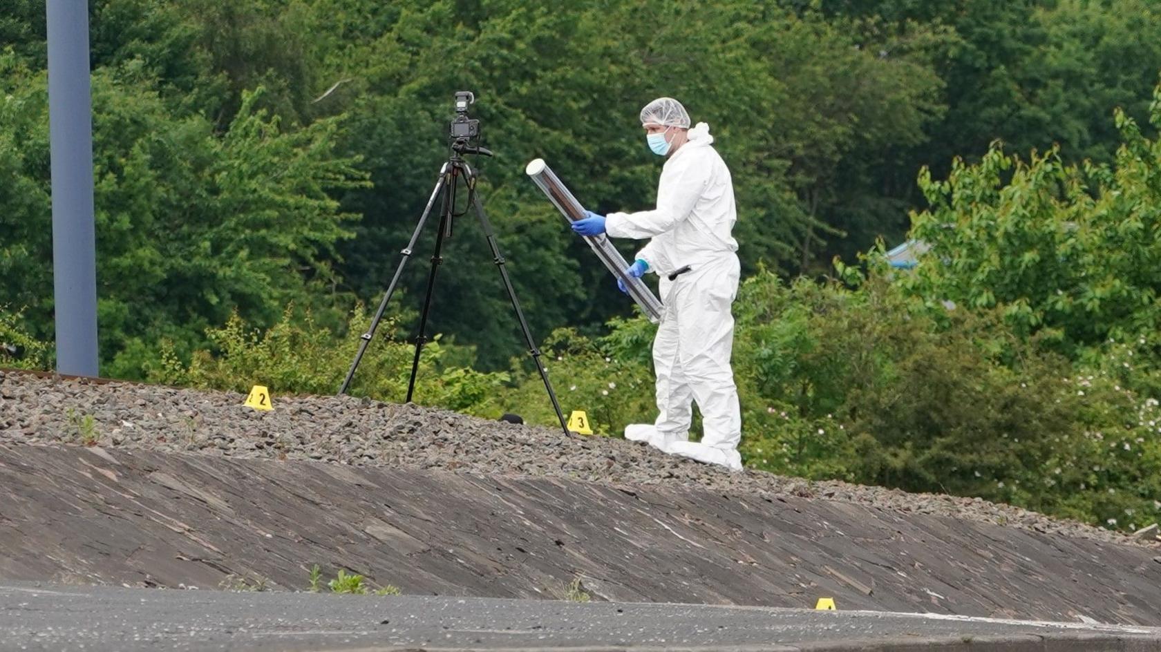 A crime scene detective wearing white holding a plastic tube