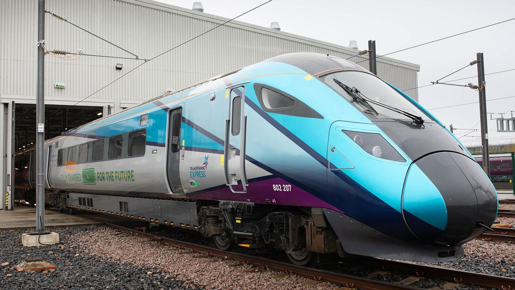 Hitachi Rail's test tri-mode train on the tracks as it leaves the company's factory in Newton Aycliffe in England. On the side the words "fully charged for the future" are written.