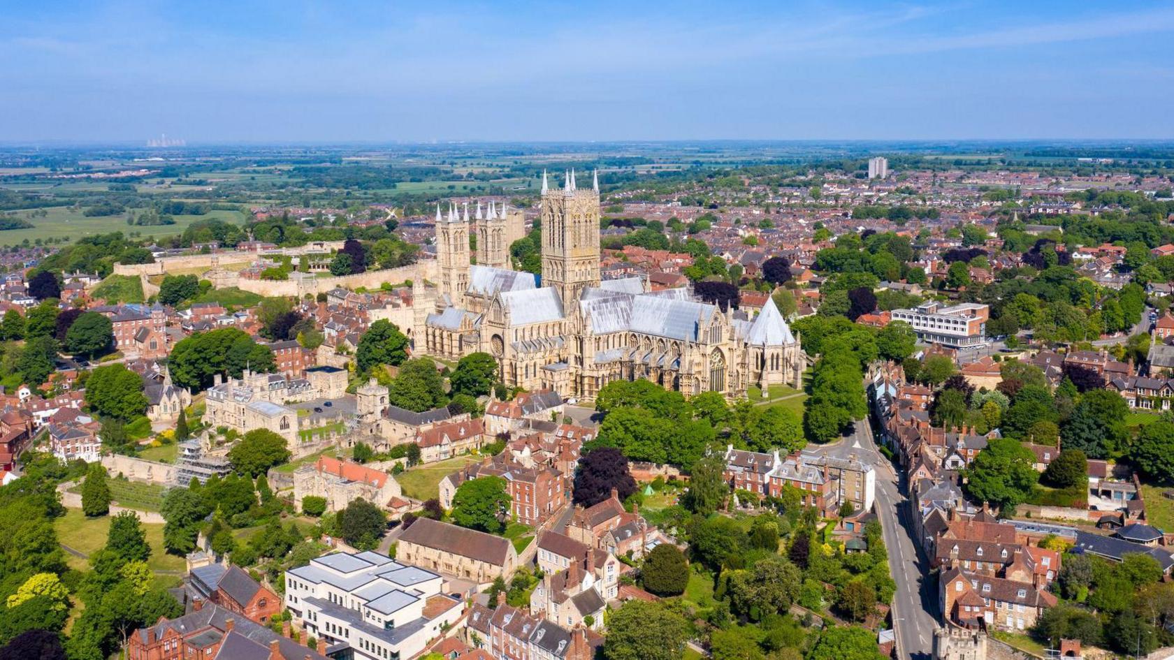 An aerial view of Lincoln Cathedral, which is surrounded by red-brick buildings and greenery.